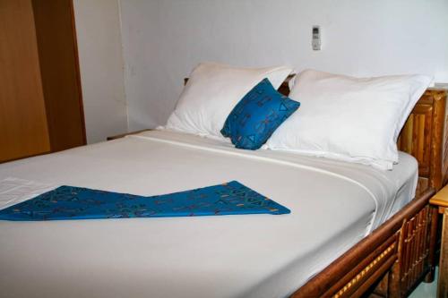 a white bed with a blue pillow on it at CONGRESS HOTEL Yaoundé in Yaoundé