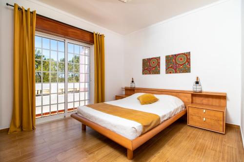 a bedroom with a bed and a large window at Villa Audiência 38 in Monte Gordo