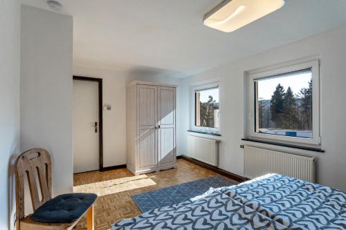 a bedroom with a bed and a chair and windows at Ferienwohnung Ankerplatz, 65qm in Langscheid