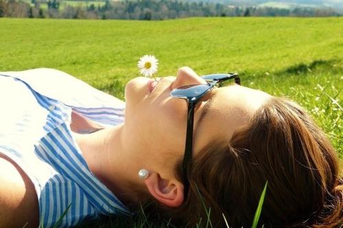 a woman laying in the grass with a flower in her glasses at Sackmann Genuss und Spa Resort in Baiersbronn