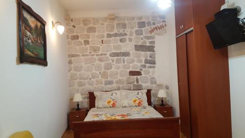 a bedroom with a bed and a stone wall at Apartments Popovic in Kotor