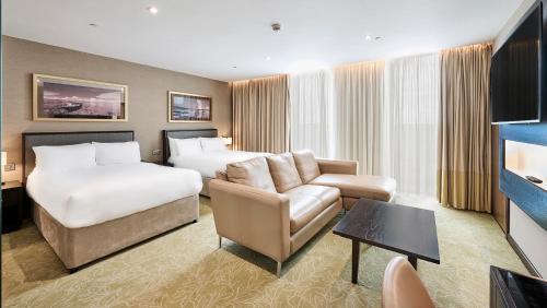 a hotel room with two beds and a couch at Genting Hotel & Spa at Resorts World Birmingham in Bickenhill