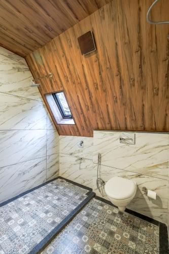 a bathroom with a toilet and a wooden ceiling at The Bagh Kufri in Kūfrī