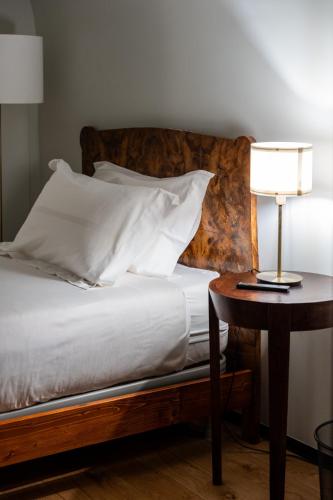 a bed with white pillows and a table with a lamp at Club64 in Andria