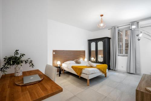une chambre avec un lit et une table avec un ordinateur portable dans l'établissement Charme & Authenticité au cœur de la vieille ville, à Saint-Laurent-du-Var