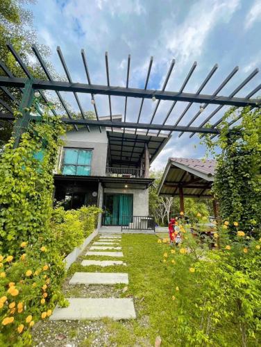 a pergola in front of a house with a garden at Por Sampao Camp&Resort in Ban Pha Saeng Lang