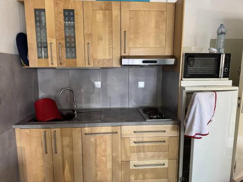 - une petite cuisine avec des placards en bois et un four micro-ondes dans l'établissement HOLIDAYLAND Résidence Les Balcons de la Méditerranée 2, à Narbonne-Plage