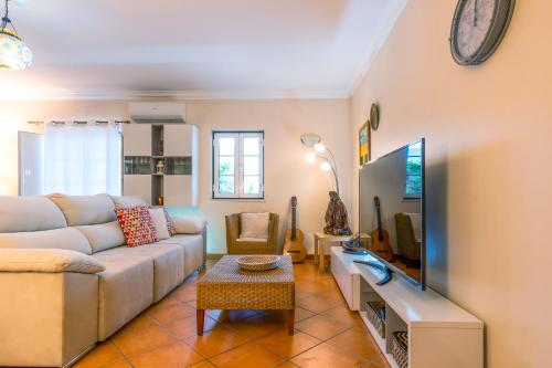 a living room with a couch and a tv at CASA DOS 2 PÁTIOS by Stay in Alentejo in Vila Nova de Milfontes