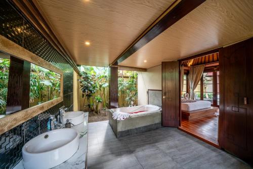 a bathroom with a tub and a sink and a bath tub at The Kampung Ubud Villa in Ubud