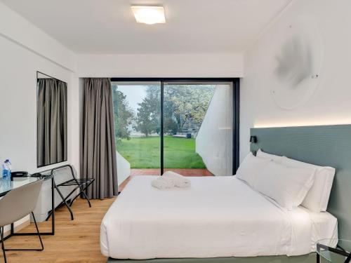 a bedroom with a bed and a desk and a window at B&B HOTEL Alba in Alba