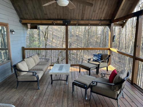eine abgeschirmte Veranda mit Sofas und einem Tisch in der Unterkunft Luxury Cabin HotTub, Hiking, Fire Pit, Game Room in Ellijay
