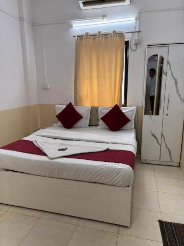 a bed with red pillows in a room with a window at Hotel Krishna Executive in Hinjewadi
