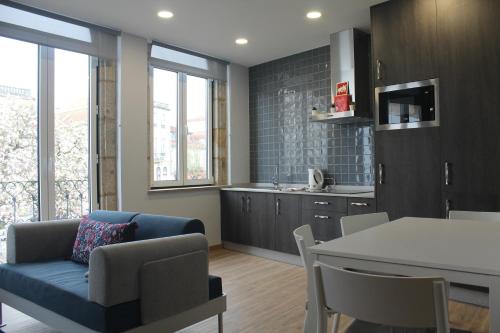 a living room with a blue couch and a kitchen at Casinhas Dom Afonso by Hotel Dom Afonso in Monção