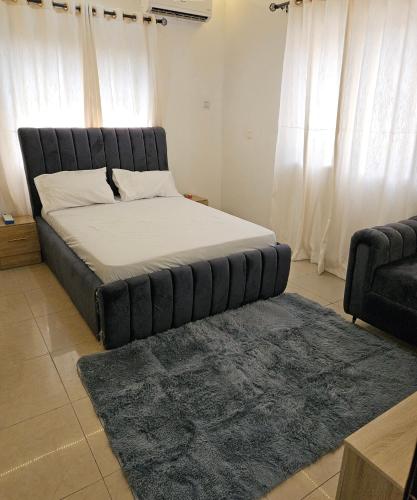a large bed in a room with a couch and a rug at Sultan Apartments Lagos in Lagos
