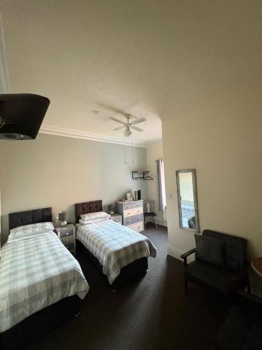 a bedroom with two beds and a chair and a mirror at The Laurels Hotel in Skegness