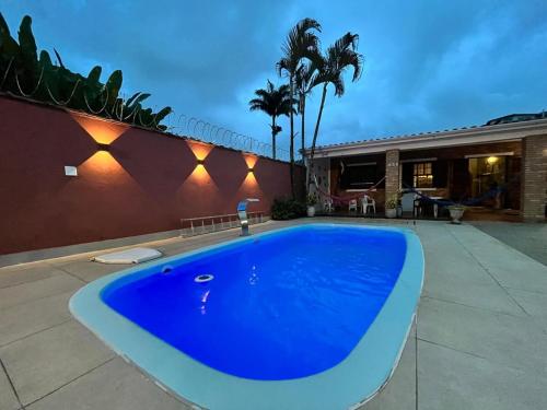 a large blue swimming pool in front of a house at Refúgio ao lado do mar com piscina e muito charme in Ubatuba