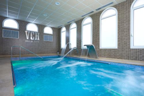 a swimming pool with blue water in a room with windows at 1881 Hotel Balneario Vichy Catalan in Caldes de Malavella