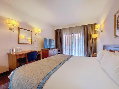 a hotel room with a large bed and a desk at Vivaldi Hotel in St Julian's