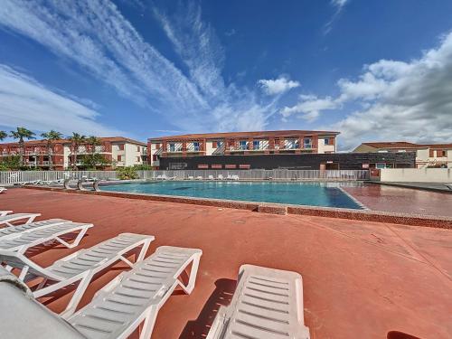 une piscine avec des chaises longues blanches et un bâtiment dans l'établissement 3652-Appartement 4 couchages avec piscine, à Argelès-sur-Mer