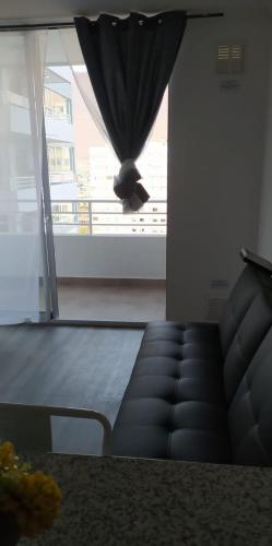 a table and a couch in a room with a window at departamento central costero in Iquique