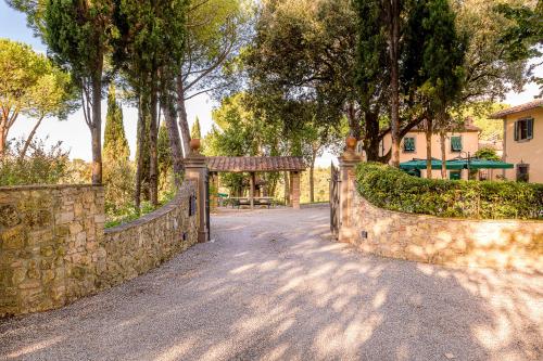 a stone fence with a gate in a yard with trees at Villa Delia Hotel and Cooking School in Ripoli