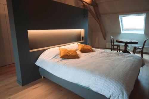 a bedroom with a bed with two orange pillows on it at Vakantiehuis Bie Jan Paté in Veurne
