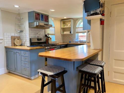 a kitchen with blue cabinets and two bar stools at Unique Stay! Converted Church In Idyllic Location in St. John's