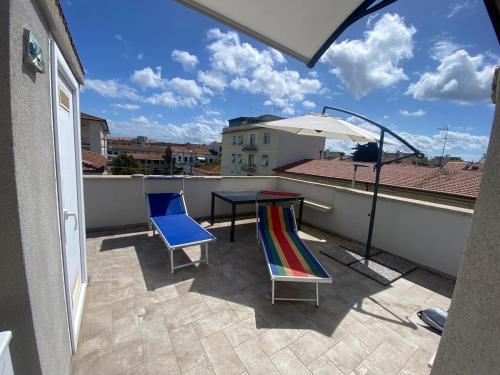 Un balcón con una mesa y sillas y una sombrilla. en La terrazza di Marco near the station, en Livorno