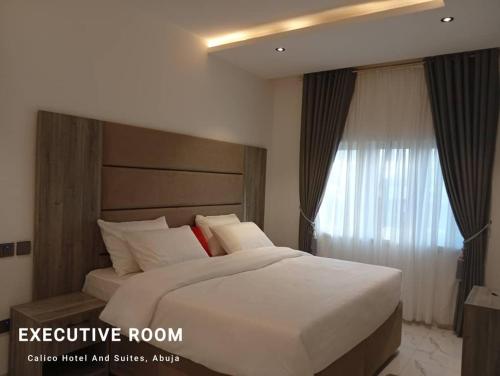 a bedroom with a large white bed and a window at Calico Hotel and Suites, Abuja in Gwarinpa