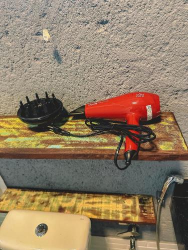a red hair dryer sitting on a wooden table at Casas de Vidro - Hospedar com Propósito in Florianópolis