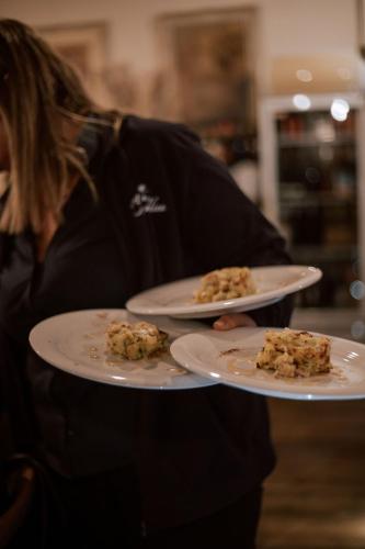 a woman holding two plates with food on them at Agriturismo La Rinaldina in Faenza