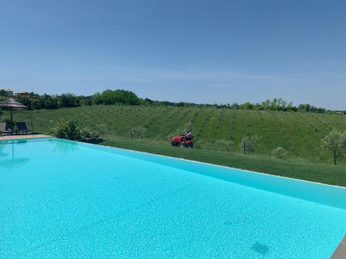 a person on a moped driving by a large blue pool at Agriturismo La Rinaldina in Faenza