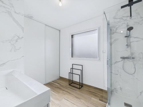 La salle de bains blanche est pourvue d'une douche et d'une fenêtre. dans l'établissement Maison moderne pour 8 à 400m de la plage, à Plouguerneau