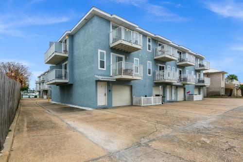a blue apartment building with balconies and a parking lot at Bikini Bottom Destin Harbor Private Gated Beach in Destin
