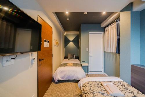 una camera con due letti e una TV a schermo piatto di UCHI Asakusabashi a Tokyo