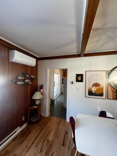 a living room with a white table and a hallway at Maison du Havre Petit Duplex in La Malbaie