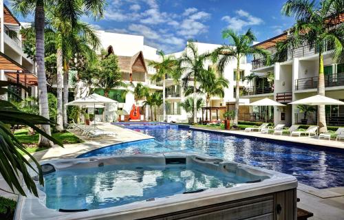 a swimming pool in front of a building with palm trees at Luxurious & Central Condo In Playa Steps From The Beach in Playa del Carmen