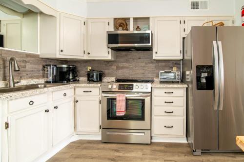 una cucina con armadi bianchi e frigorifero in acciaio inossidabile di Windy Waves Top Location w Pool a Myrtle Beach