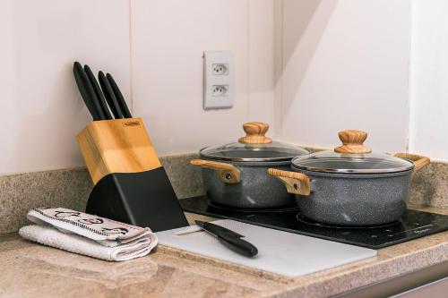 two pots on a stove with a cutting board at Go Vila Mariana - Studio 7 min. a pé do Metrô in Sao Paulo