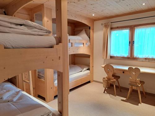 a room with three bunk beds and a desk at Laax Chalet by Quokka 360 - Charming Chalet with private patio in Laax