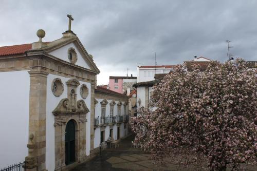 a building with a flowering tree in front of it at Casinhas Dom Afonso by Hotel Dom Afonso in Monção