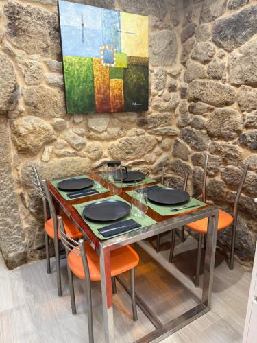 a table with chairs and a painting on a stone wall at La Casa del Horreo in Combarro