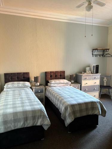 a bedroom with two beds and a dresser at The Laurels Hotel in Skegness