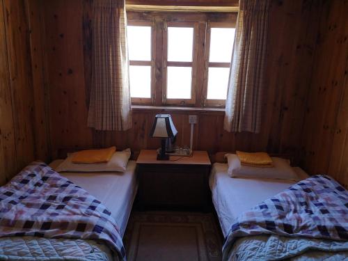 two twin beds in a room with a window at Lukla Himalaya Lodge in Lukla
