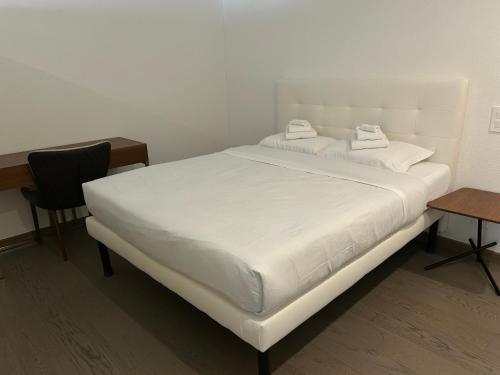 a white bed in a room with a desk and a chair at Moderno appartamento a Tenero in Tenero
