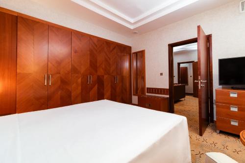 a bedroom with a bed and wooden cabinets and a television at Holiday Inn - Suites Kuwait Salmiya by IHG in Kuwait