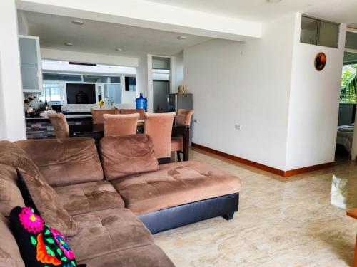 a living room with a brown couch and a kitchen at Hotel Krammer en San Ramón, Selva Central in San Ramón