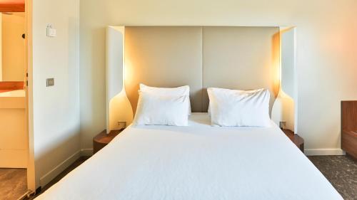 a bedroom with a large white bed with two pillows at Campanile La Roche Sur Yon Centre Gare in La Roche-sur-Yon