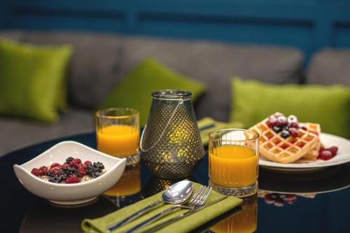 a table with a plate of breakfast foods and orange juice at Benefice Hotel Yerevan-通緝 in Yerevan
