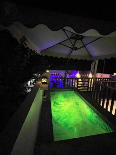 a swimming pool at night with an umbrella at Couple - Private Jacuzzi Pool in Mabalacat